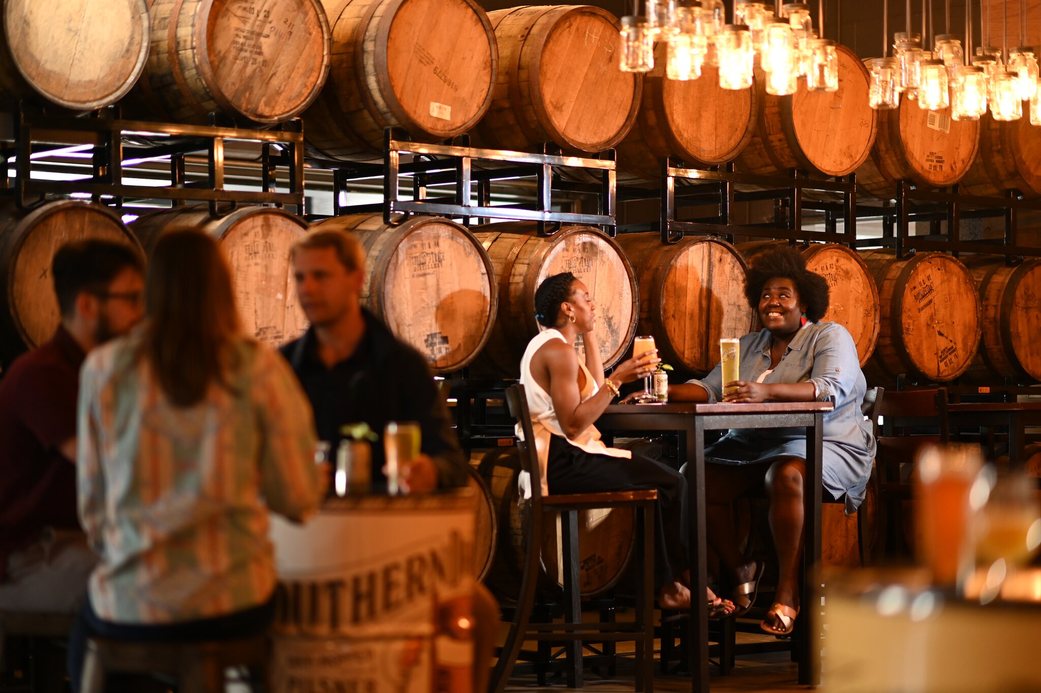 people at a brewery with barrels in the background