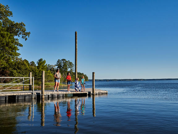 A family fishes from the boardwalk at South Toledo Bend State Park, with a beautiful view of the reservoir in the background.