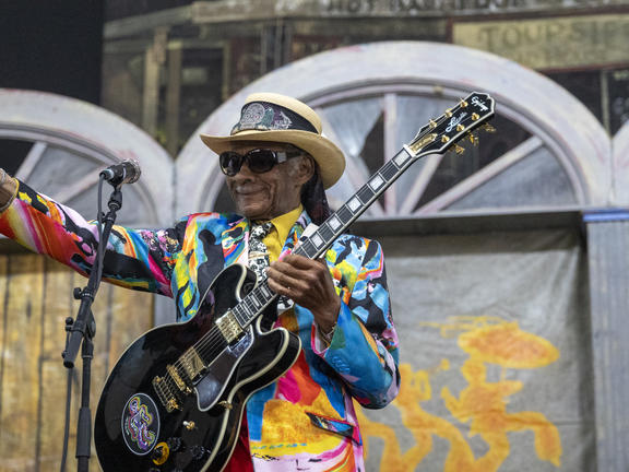 A. blues performer smiles at a JazzFest crowd.