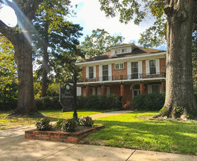 Exterior of the Steel Magnolia House surrounded by massive trees in Natchitoches.