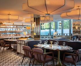 The interior of Miss River in New Orleans offers a chic, diner-esque vibe with black-and-white tiled floors, dimmed overhead lighting and mirrors behind the bar.