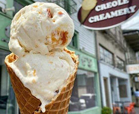 A waffle cone holds two scoops of creamy ice creams outside The Creole Creamery in New Orleans.