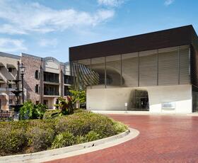 Exterior of a brick building next to a modern museum building, with a fountain in front of them