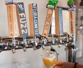 A person pours a hazy draft beer from a row of custom tap handles at Parish Brewing Company.