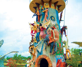 A colorful tower with statues poised as if they were climbing it at the Chauvin Sculpture Garden in South Louisiana.