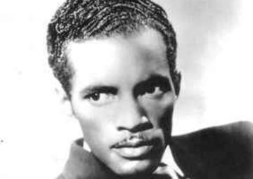 A portrait of Percy Mayfield in a suit and tie. He looks off into the distance.