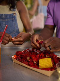 Two people peel crawfish together.
